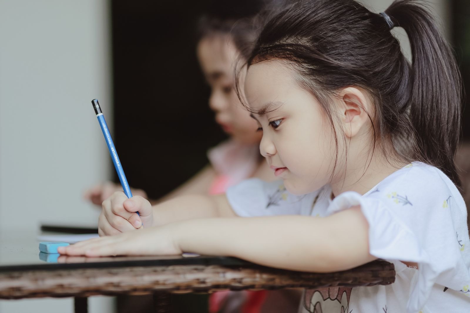 Two young children drawing together with coloured pencils